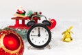 Alarm clock, santa claus on a sleigh, a spruce branch, a golden bell and a Christmas tree toy ball on a snow background Royalty Free Stock Photo