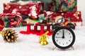 Alarm clock, santa claus sleigh, boxes with gifts, christmas tree cone and golden bell on a background of snow Royalty Free Stock Photo