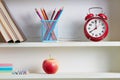 Alarm clock and school supplies on shelf