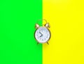 Alarm clock showing eight o`clock on bright duo tone yellow neon green background. Flat lay. Morning sunlight. New day beginning