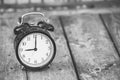 Alarm clock showing five o`clock on wooden background, black and white image. Royalty Free Stock Photo