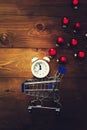 Alarm clock showing midnight, small cart and multi-colored Christmas balls on a wooden background