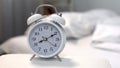 Alarm clock showing morning time on night table near bed, sleeping hours Royalty Free Stock Photo