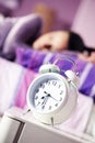 Alarm clock with a sleeping young woman Royalty Free Stock Photo