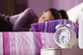An alarm clock with a sleeping young woman Royalty Free Stock Photo