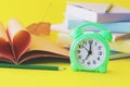 Alarm clock, stack of books and stationery on yellow background, back to school, holidays, education Royalty Free Stock Photo