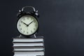 Alarm clock on stack of textbook with chalkboard or blackboard background copy space, time for reading, concentration in study, Royalty Free Stock Photo