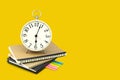 Alarm clock stacked on brown and black notebook with a post it note paper. Isolated on yellow background with copy space and clipp Royalty Free Stock Photo
