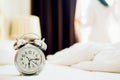 Alarm clock standing on bedside table has already rung early morning to wake up woman is stretching in bed in