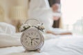 Alarm clock standing on bedside table has already rung early morning to wake up woman is stretching in bed in