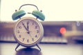 Alarm clock is standing on a grey desk, office stuff in the blurry background Royalty Free Stock Photo