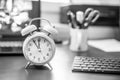 Alarm clock is standing on a grey desk, office stuff in the blurry background Royalty Free Stock Photo