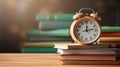 Alarm clock stands on top of a stack of colored books on table, blurred library background, copy space, back to school concept Royalty Free Stock Photo