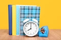Alarm clock and stationery on the table, on a yellow background. Royalty Free Stock Photo
