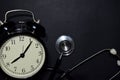 Alarm clock, stethoscope on black background Royalty Free Stock Photo