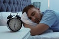 Alarm clock on table and young man sleeping in bed Royalty Free Stock Photo