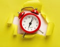 Alarm clock at torn yellow paper background