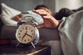 Alarm clock, wake up and man sleeping in the bedroom of his modern apartment in the morning. Lazy, resting and hand of Royalty Free Stock Photo
