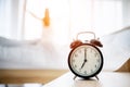 Alarm clock wake up and woman standing open curtain window in bedroom Royalty Free Stock Photo