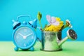 Alarm clock and watering can with flowers on the table. Concept on the topic of watering plants on time