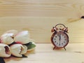 Alarm clock and white flowers in pink vase on brown wood table Royalty Free Stock Photo