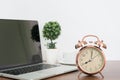 Alarm clock on wood table with tree vase and laptop Royalty Free Stock Photo