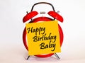 An alarm clock and a yellow note with text happy Birthday baby. Royalty Free Stock Photo