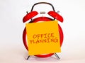 An alarm clock and a yellow note with text office planning. Royalty Free Stock Photo