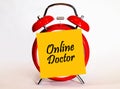 An alarm clock and a yellow note with text online doctor. Royalty Free Stock Photo