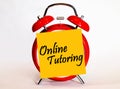 An alarm clock and a yellow note with text online tutoring.