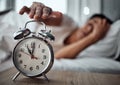 Alarm, morning and a hand with a clock for awake, oversleep or tired in the bedroom of a home. House, ring and a closeup Royalty Free Stock Photo