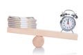 Alarmclock and dollar bundles balancing on seesaw