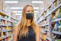 Alarmed female wears medical mask against coronavirus while grocery shopping in supermarket or store- health, safety and Royalty Free Stock Photo