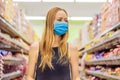 Alarmed female wears medical mask against coronavirus while grocery shopping in supermarket or store- health, safety and Royalty Free Stock Photo