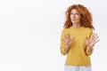 Alarmed and worried curly redhead woman calm down person, saying dont shoot, raising arms, begging to stop, look freak