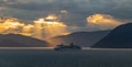 Alaska, USA - June 22 , 2018: Celebrity Infinity sailing at sunset in one of the Alaskan Fjords. Beautiful orange sky with sunrays