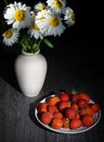 Alba daisies, Natural white daisies stand in a white plaster jug, next to a plate with fresh strawberries. This still life is on a Royalty Free Stock Photo