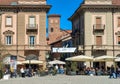 Historic buildings on town square and medieval tower on background in Alba, Italy