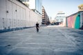 Albino man with his guitar and hat walking away down a completely empty pedestrian street Royalty Free Stock Photo