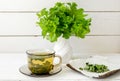 Alchemilla vulgaris, common lady\'s mantle medicinal herbal tea in clear cup. Fresh lady\'s mantle plants in vase.