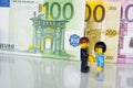 Alcobendas, Spain - May 14, 2018: Handshake betwen a woman and a man for an agreement on euro bills background, Lego minifigures