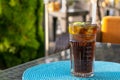 Alcohol cocktail - Long Island Iced Tea. Iced tea with lemon in a glass. Brown ice drink on table an outdoor in a cafe.