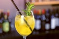 Alcohol cocktail with sparkling wine, ice and liquor , lemon and rosemary in wineglass on bar counter, close-up view.