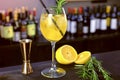 Alcohol cocktail with sparkling wine, ice and liquor , lemon and rosemary in wineglass on bar counter, close-up view.