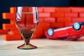 Alcohol and driving concept. Shot glass and a broken car Royalty Free Stock Photo