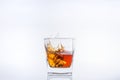 Alcohol in the glass. Ice cube falls into a glass with splashes. Isolated on white background. Royalty Free Stock Photo