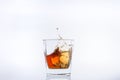 Alcohol in the glass. Ice cube falls into a glass with splashes. Isolated on white background. Royalty Free Stock Photo