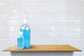 Alcohol sanitizer hand gel cleaners big size and small size for anti virus on wood shelf at white ceramic tile wall pattern