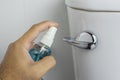 Alcohol sanitizer spray in hand is cleaning into toilet flush handle. Royalty Free Stock Photo