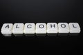 Alcohol,text word title caption label cover backdrop background. Alphabet letter toy blocks on black reflective